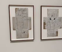 A photo of a Yoshitomo Nara piece on cardboard of a young girl with a gun next to text saying: I am left wing, I am right wing '